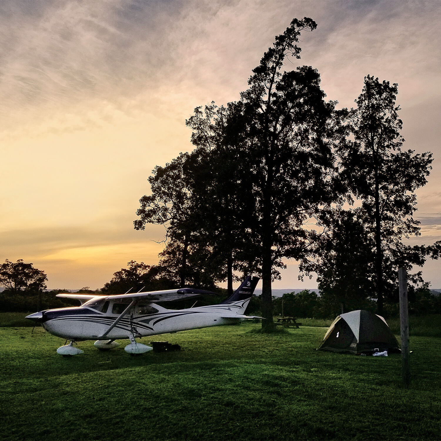 Cessna Skylane at a camp site next to a tent.