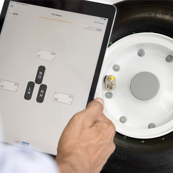 Aircraft wheel with tire pressure sensor and tablet displaying tire pressure values.